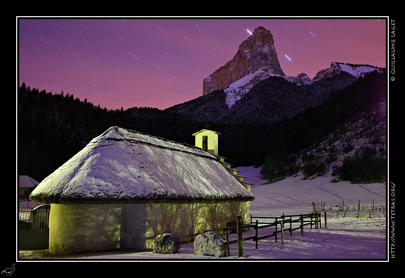 Mont Aiguille : La chapelle de Trézanne et son toit de chaume récemment restauré sont blottis au pied du Mont Aiguille.Un peu de voile nuageux
 dans le ciel s'éclaire alors que les étoiles terminent leur nuit
 
